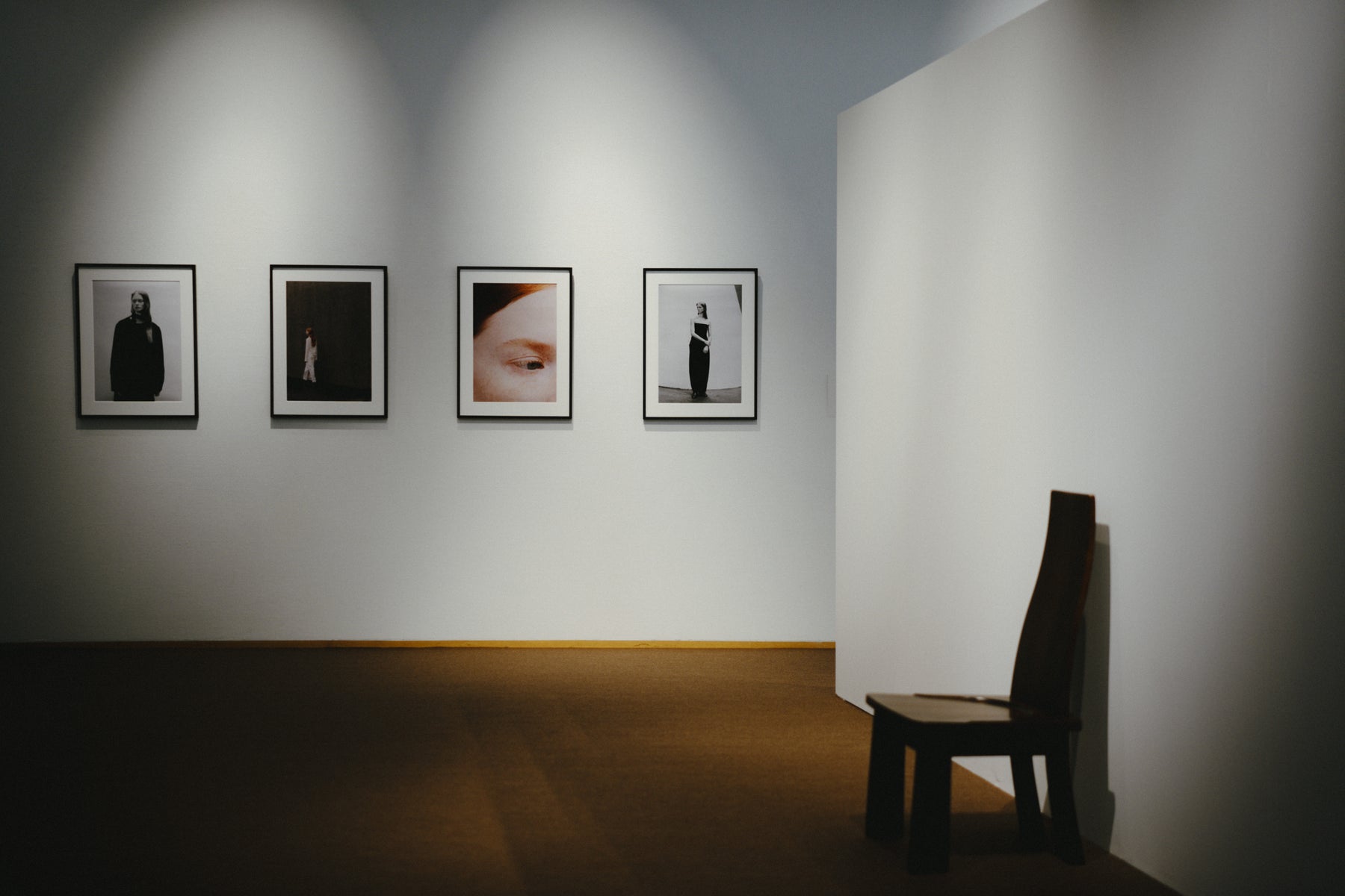 四つの額装写真と一脚の木の椅子が置かれた展示室。